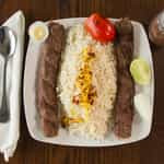 Two Skewers Of Delicious Ground Beef Served With Roasted Tomato And Basmati Rice.