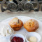 2 homemade scones served with jam, butter and fresh cream