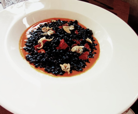 Fregola Al Nero Di Seppia Con Ricci Di Mare E Vongole Su Crema Di Datterino Giallo